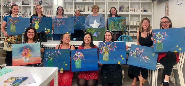 ladies showing flower paintings on paint night with Chrissie Richards
